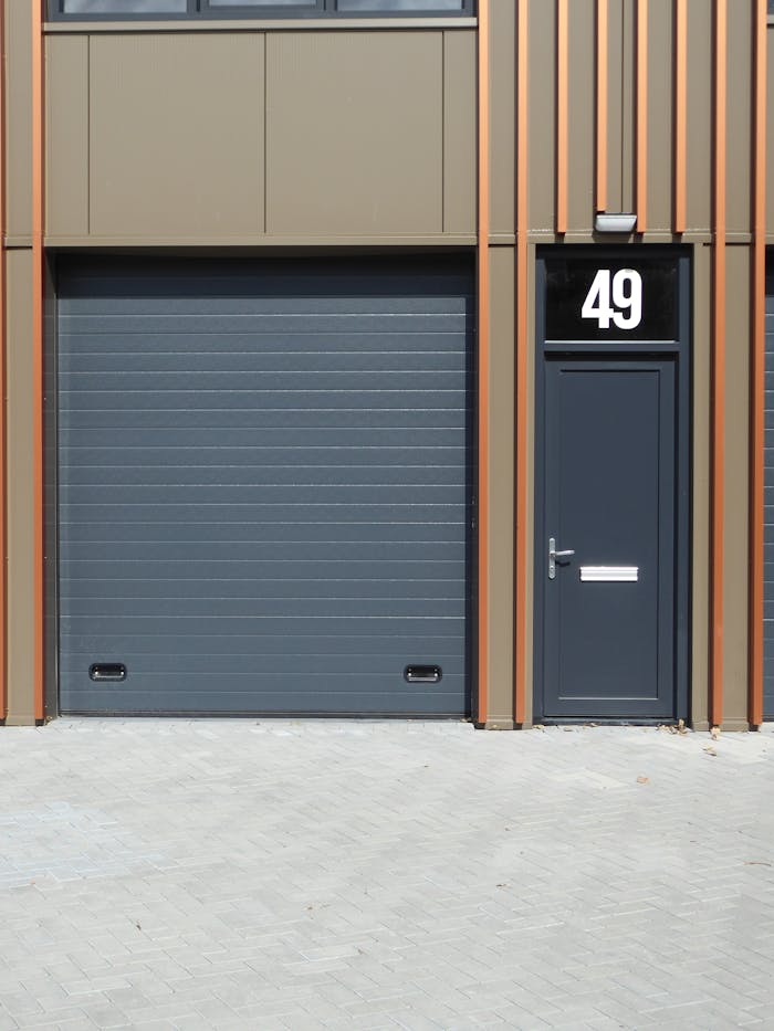 A contemporary building facade featuring a dark garage door and entrance with number 49.